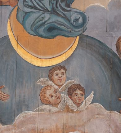 Zdjęcie nr 8: Polichromia skomponowana na pozornym, drewnianym sklepieniu kolebkowym przedstawia Wniebowzięcie Najświętszej Marii Panny. W centrum kompozycji Maria stoi na globie i półksiężycu i wyciąga przed siebie ręce. Ma pociągłą twarz, ciemne oczy, szeroki nos i niewielkie usta. Jest ubrana w białą suknię i takiego koloru welon, którego końce rozwiewają się z przodu i z tyłu. Jej nogi otacza niebieski płaszcz z żółtym podbiciem, które wywija się na wysokości lewego biodra Marii. Zza jej głowy rozchodzi się gloria promienista, ponad którą unosi się nimb z 12 gwiazd i zamknięta korona z czerwoną i niebieską szarfą. Powyżej, między obłokami niewielka, złota gwiazda. Półksiężyc pod jej stopami jest ciemnożółty, ze złotym brzegiem, glob jest niebieski, podtrzymują go dwa anioły w jasnych sukniach z długimi rękawami. Scenę otaczają skłębione różowo-niebieskie obłoki, spomiędzy których wyłaniają się w wielu miejscach główki anielskie. W czterech narożnikach znajdują się anioły ubrane w jasne suknie i owijające częściowo ich ciała ciemnożółte (w przypadku jednego niebieski) płaszcze. Każdy z nich trzyma banderolę z łacińskim napisem: „ATTOLITE PORTAS PRINCIPES V[E]STRAS, ps(almi) 23”, „QUAE EST ISTA QUAE ASCENDIT Can[ticum] 6”, „PULCHRA UT LUNA ELLECTA UT SOL”, „ENI CORONABERIS, Cant[icum]”. Scenę z dwóch stron ograniczają pasy polichromii imitującej niebieską marmoryzację. 
