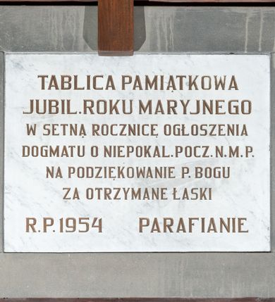 Zdjęcie nr 1: Tablica w kształcie leżącego prostokąta wykonana z marmuru i obwiedziona szeroką, gładką ramą z szarego kamienia. Na niej majuskułowy, złocony napis „TABLICA PAMIĄTKOWA / JUBIL(EUSZ) ROKU MARYJNEGO / W SETNĄ ROCZNICĘ OGŁOSZENIA / DOGMATU O NIEPOKAL(ANYM) POCZ(ĘCIU) N(AJŚWIĘTSZEJ) M(ARII) P(ANNY) / NA PODZIĘKOWANIE P(ANU) BOGU / ZA OTRZYMANE ŁASKI / R(OKU) P(AŃSKIEGO) 1954 PARAFIANIE”. 