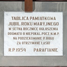 Zdjęcie nr 1: Tablica w kształcie leżącego prostokąta wykonana z marmuru i obwiedziona szeroką, gładką ramą z szarego kamienia. Na niej majuskułowy, złocony napis „TABLICA PAMIĄTKOWA / JUBIL(EUSZ) ROKU MARYJNEGO / W SETNĄ ROCZNICĘ OGŁOSZENIA / DOGMATU O NIEPOKAL(ANYM) POCZ(ĘCIU) N(AJŚWIĘTSZEJ) M(ARII) P(ANNY) / NA PODZIĘKOWANIE P(ANU) BOGU / ZA OTRZYMANE ŁASKI / R(OKU) P(AŃSKIEGO) 1954 PARAFIANIE”. 
