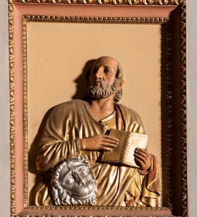 Zdjęcie nr 4: Ambona przyścienna składająca się z kosza, zaplecka, baldachimu i schodów z balustradą, zawieszona przy wschodnim filarze nawy. Kosz na planie sześcioboku, w narożach  ustawiono pilastry wsparte na cokołach, pomiędzy którymi prostokątne pola. Wszystkie płaszczyzny zdobione prostokątnymi płycinami dekorowanymi płaskorzeźbionymi postaciami ewangelistów oraz Chrystusa ukazanymi w półpostaci. Każdy z ewangelistów jest ubrany w długą złotą suknię i złoty płaszcz, trzyma w rękach otwartą księgę (św. Jan zwój), towarzyszy mu atrybut umożliwiający identyfikację. Chrystus jest ustawiony frontalnie, prawą ręką błogosławi, w lewej trzyma jabłko królewskie. Ma opadające na ramiona, zwinięte w pukle włosy oraz brodę. Podstawa kosza stożkowata, ujęta w narożach listwami, z pozłacaną szyszką od dołu. Zaplecek w kształcie prostokąta z płyciną ujętą pilastrami, wewnątrz której aplikowany stylizowany ornament roślinny. Baldachim powtarzający plan kosza, ujęty profilowanym gzymsem, wyłamanym w narożach, zwieńczony pełnoplastyczną figurą Chrystusa Zmartwychwstałego trzymającego krzyż, ustawioną na wielobocznej podstawie wspartej na sześciu wolutach. Chrystus został ukazany w całej postaci, z prawą ręką uniesioną w geście błogosławieństwa, lewą przytrzymującą krzyż. Ma owalną twarz okoloną długimi włosami, które spływają mu na ramiona i plecy; nad głową okrągły nimb. Jest ubrany w długą suknię, na którą ma zarzucony płaszcz spięty na ramionach. Obie szaty łamią się ostrymi fałdami. W podniebiu baldachimu znajduje się podwójna, ośmioramienna gwiazda wydzielona pozłacanymi listwami, z lampą na środku. Balustrada z profilowaną poręczą, artykułowana romboidalnymi płycinami i pilastrami. Kolorystyka pastelowa, jasna. Struktura w kolorze jasnoszarym, płyciny jasnobeżowe, detal architektoniczny, ornamenty oraz szaty pozłacane, atrybuty ewangelistów posrebrzane.