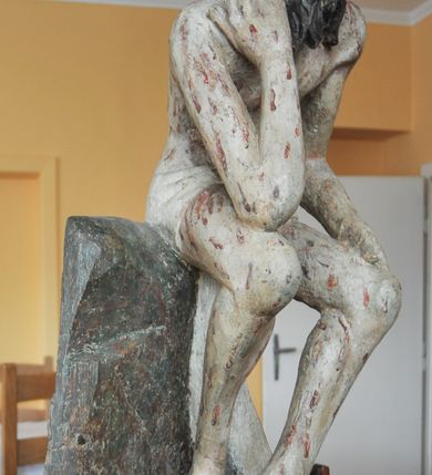 Zdjęcie nr 1: Rzeźba pełna, całopostaciowa, ustawiona na niewysokim cokole. Chrystus ukazany w pozycji siedzącej, na podstawie imitującej blok skalny. Prawą ręką, opartą na udzie  podtrzymuje głowę, lewą dłoń opiera na lewej nodze; kolana ma rozchylone, lewą stopę ustawioną przed prawą. Chrystus ma pociągłą twarz o wydatnych kościach policzkowych, wąskie brwi opadające prostą linią w dół, długi nos, zagłębione oczy i wyraźnie zaznaczone usta. Długie włosy opadają mu na ramiona i plecy, broda dzieli się w dwa pukle; na głowie grube zwoje korony cierniowej.  Biodra ma przepasane białym perizonium, którego długi, wolny koniec opada między udami i za lewą nogą aż na podłoże. Na całym ciele zaznaczono ślady męki – równomiernie rozmieszczone krople spływającej krwi. W partiach ciała polichromia naturalistyczna.