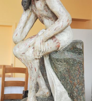 Zdjęcie nr 3: Rzeźba pełna, całopostaciowa, ustawiona na niewysokim cokole. Chrystus ukazany w pozycji siedzącej, na podstawie imitującej blok skalny. Prawą ręką, opartą na udzie  podtrzymuje głowę, lewą dłoń opiera na lewej nodze; kolana ma rozchylone, lewą stopę ustawioną przed prawą. Chrystus ma pociągłą twarz o wydatnych kościach policzkowych, wąskie brwi opadające prostą linią w dół, długi nos, zagłębione oczy i wyraźnie zaznaczone usta. Długie włosy opadają mu na ramiona i plecy, broda dzieli się w dwa pukle; na głowie grube zwoje korony cierniowej.  Biodra ma przepasane białym perizonium, którego długi, wolny koniec opada między udami i za lewą nogą aż na podłoże. Na całym ciele zaznaczono ślady męki – równomiernie rozmieszczone krople spływającej krwi. W partiach ciała polichromia naturalistyczna.