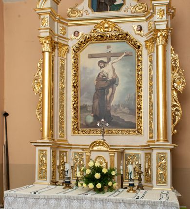 Zdjęcie nr 4: Ołtarz architektoniczny, przyścienny, jednokondygnacyjny, jednoosiowy ze zwieńczeniem. Mensa w typie sarkofagowym, na wysokim cokole, gładka, górna partia cokołu oddzielona profilowanymi listwami. Na mensie ustawiono tabernakulum w formie prostopadłościennej szafki, ze ścianką frontową ujętą kanelowanymi pilastrami jońskimi wspierającymi gzyms, pośrodku przyczółek utworzony z dwóch stykających się wolut, wypełniony muszlą. Drzwiczki w kształcie stojącego prostokąta zamknięte łukiem półkolistym nadwieszonym z przedstawieniem kielicha z hostią. 
Nastawa ustawiona na wysokim cokole ujęta parami pilastrów, z których wewnętrzne ustawione ukośnie oraz stojącymi na ich tle kolumnami, podtrzymującymi odcinki belkowania oraz fragmenty naczółków. Pole środkowe z wnęką w kształcie stojącego prostokąta o ściętych górnych narożach, ujęte ozdobną ramą wypełnioną ażurowym ornamentem akantowym. W niej obraz z przedstawienie św. Franciszka obejmującego ukrzyżowanego Chrystusa. Pola cokołów i pilastrów są wypełnione stylizowaną wicią akantu, boki ołtarza flankowane ażurową wicią akantową z rozetą. Zwieńczenie ujęte spływami wolutowymi, zakończone gzymsem w kształcie łuku półkolistego nadwieszonego. W zwieńczeniu płaskorzeźbione przedstawienie św. Antoniego Padewskiego w prostokątnej ramie o ściętych ćwierćkoliście dolnych narożach i zakończonej łukiem nadwieszonym z uskokiem. Całość struktury ołtarza polichromowana w kremowym odcieniu, wnętrza płycin szare, detal architektoniczny i ornamenty pozłacane.