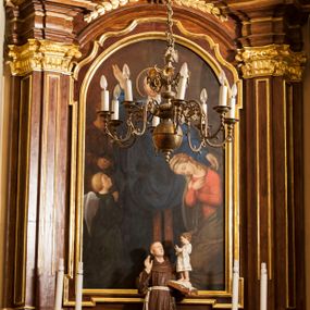 Zdjęcie nr 1: Nastawa ołtarzowa przyścienna, architektoniczna, jednoosiowa, jednokondygnacyjna ze zwieńczeniem, ustawiona na wysokim cokole. Mensa skrzyniowa, prostopadłościenna z portatylem w formie kamiennej płytki; ustawiona na niskim cokole, o profilu wklęsło-wypukłym, profilowana. Na niej ustawiono prostopadłościenny postument, na którym stoi figura św. Antoniego Padewskiego. Święty ukazany frontalnie, w lekkim kontrapoście. Prawą rękę unosi do góry, na lewej trzyma otwartą księgę, na której stoi Dzieciątko Jezus błogosławiące świętego. Antoni jest ubrany w habit franciszkański, Dzieciątko w białą, przepasaną sukienkę. Wysoki cokół nastawy zdobią płyciny oraz dwie plakiety dekoracyjne utworzone z liści akantu i girland kwiatowych. Nastawa ołtarzowa flankowana parą zwielokrotnionych pilastrów o stylizowanych głowicach kompozytowych, wspierających odcinki belkowania zwieńczone silnie wysuniętym, profilowanym gzymsem. W polu środkowym obraz z przedstawieniem św. Aleksandra (?) w kształcie prostokąta zamkniętego półkoliście, ujętego w ramę z uszakami w dolnych narożach i górą o profilu wklęsło-wypukłym. Powyżej ramy rząd kampanul zbiegających się do centralnie umieszczonej woluty. Zwieńczenie bogato dekorowane, wklęsło-wypukłe, ujęte po bokach taśmami o spiralnie skręconych końcach, dekorowanymi kampanulami i liśćmi. Pośrodku pełnoplastyczna figura św. Jana Nepomucena na profilowanym cokole, na tle glorii promienistej otoczonej obłokami. Ponad zwieńczeniem promienie w półokręgu. Całość struktury ołtarza drewniana, bejcowana na odcień ciemnobrązowy; detal architektoniczny pozłacany; obłoki srebrzone; figura św. Antoniego polichromowana naturalistycznie. 