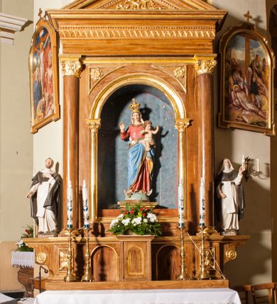 Zdjęcie nr 2: Ołtarz przyścienny, architektoniczny, jednoosiowy, jednokondygnacyjny. Mensa skrzyniowa z kamiennym portatylem, poprzedzona dwoma, masywnymi kolumienkami o kostkowych kapitelach. Antepedium artykułowane czterema prostokątnymi płycinami zamkniętymi półkoliście. Na mensie, na kolumienkach blat ołtarza. Na nim prostopadłościenne tabernakulum z drzwiczkami akcentowanymi płyciną w kształcie prostokąta zamkniętego półkoliście. Cokół nastawy ołtarza pięciodzielny z analogicznymi, większymi płycinami. Wysunięte osie cokołu są dekorowane plakietą z motywem roślinnym, zaś skrajne są ozdobione konsolami z aplikowaną, okrągłą rozetą. Pole środkowe z prostokątną wnęką zamkniętą półkoliście, z łukiem wspartym na dwóch kolumnach korynckich. We wnęce na malowanym tle gwieździstego nieba figura Matki Boskiej z Dzieciątkiem. Powyżej, w narożach przyłuczy rzeźbione rozety w trójkątnych polach. Nastawa flankowana parą kolumn korynckich ustawionych na wysuniętych partiach cokołu oraz figurami św. Dominika po lewej i św. Katarzyny Sieneńskiej po prawej stronie. Kolumny wspierają belkowanie zwieńczone trójkątnym przyczółkiem wypełnionym monogramem maryjnym; fryz zdobi ornament zygzakowaty. Za tympanonem pozłacana kopuła pokryta motywem rybiej łuski, zwieńczona krzyżem postawionym na kuli flankowanej motywami roślinnymi. Całość ołtarza fladrowana w odcieniu ciemnobrązowym, detal architektoniczny złocony, polichromia rzeźb w partiach ciała naturalistyczna.