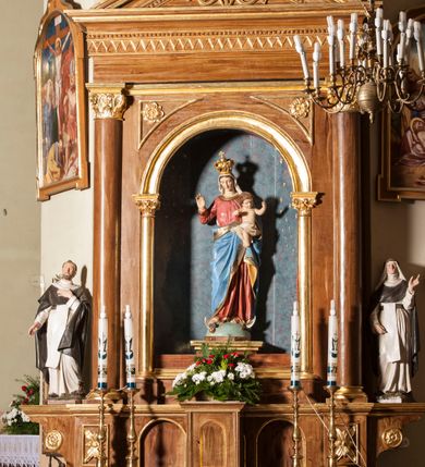 Zdjęcie nr 1: Ołtarz przyścienny, architektoniczny, jednoosiowy, jednokondygnacyjny. Mensa skrzyniowa z kamiennym portatylem, poprzedzona dwoma, masywnymi kolumienkami o kostkowych kapitelach. Antepedium artykułowane czterema prostokątnymi płycinami zamkniętymi półkoliście. Na mensie, na kolumienkach blat ołtarza. Na nim prostopadłościenne tabernakulum z drzwiczkami akcentowanymi płyciną w kształcie prostokąta zamkniętego półkoliście. Cokół nastawy ołtarza pięciodzielny z analogicznymi, większymi płycinami. Wysunięte osie cokołu są dekorowane plakietą z motywem roślinnym, zaś skrajne są ozdobione konsolami z aplikowaną, okrągłą rozetą. Pole środkowe z prostokątną wnęką zamkniętą półkoliście, z łukiem wspartym na dwóch kolumnach korynckich. We wnęce na malowanym tle gwieździstego nieba figura Matki Boskiej z Dzieciątkiem. Powyżej, w narożach przyłuczy rzeźbione rozety w trójkątnych polach. Nastawa flankowana parą kolumn korynckich ustawionych na wysuniętych partiach cokołu oraz figurami św. Dominika po lewej i św. Katarzyny Sieneńskiej po prawej stronie. Kolumny wspierają belkowanie zwieńczone trójkątnym przyczółkiem wypełnionym monogramem maryjnym; fryz zdobi ornament zygzakowaty. Za tympanonem pozłacana kopuła pokryta motywem rybiej łuski, zwieńczona krzyżem postawionym na kuli flankowanej motywami roślinnymi. Całość ołtarza fladrowana w odcieniu ciemnobrązowym, detal architektoniczny złocony, polichromia rzeźb w partiach ciała naturalistyczna.