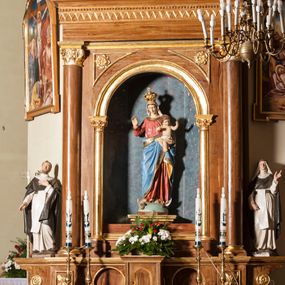 Zdjęcie nr 1: Ołtarz przyścienny, architektoniczny, jednoosiowy, jednokondygnacyjny. Mensa skrzyniowa z kamiennym portatylem, poprzedzona dwoma, masywnymi kolumienkami o kostkowych kapitelach. Antepedium artykułowane czterema prostokątnymi płycinami zamkniętymi półkoliście. Na mensie, na kolumienkach blat ołtarza. Na nim prostopadłościenne tabernakulum z drzwiczkami akcentowanymi płyciną w kształcie prostokąta zamkniętego półkoliście. Cokół nastawy ołtarza pięciodzielny z analogicznymi, większymi płycinami. Wysunięte osie cokołu są dekorowane plakietą z motywem roślinnym, zaś skrajne są ozdobione konsolami z aplikowaną, okrągłą rozetą. Pole środkowe z prostokątną wnęką zamkniętą półkoliście, z łukiem wspartym na dwóch kolumnach korynckich. We wnęce na malowanym tle gwieździstego nieba figura Matki Boskiej z Dzieciątkiem. Powyżej, w narożach przyłuczy rzeźbione rozety w trójkątnych polach. Nastawa flankowana parą kolumn korynckich ustawionych na wysuniętych partiach cokołu oraz figurami św. Dominika po lewej i św. Katarzyny Sieneńskiej po prawej stronie. Kolumny wspierają belkowanie zwieńczone trójkątnym przyczółkiem wypełnionym monogramem maryjnym; fryz zdobi ornament zygzakowaty. Za tympanonem pozłacana kopuła pokryta motywem rybiej łuski, zwieńczona krzyżem postawionym na kuli flankowanej motywami roślinnymi. Całość ołtarza fladrowana w odcieniu ciemnobrązowym, detal architektoniczny złocony, polichromia rzeźb w partiach ciała naturalistyczna.