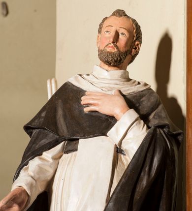 Zdjęcie nr 3: Rzeźba pełnoplastyczna, całopostaciowa, wydrążona od tyłu, na cokole.  Święty Dominik został ukazany frontalnie, w kontrapoście, z ciężarem na prawej nodze i sylwetką odchyloną do tyłu. Prawą rękę ma wysuniętą przed siebie, lewą składa na piersi. Głowę ma nieznacznie uniesioną, twarz pociągłą, okoloną krótką, brązową brodą i krótkimi, kręconymi włosami, czoło wysokie, wzrok skierowany ku górze. Święty jest ubrany w habit dominikański: białą tunikę przewiązaną czarnym pasem, biały szkaplerz oraz długą czarną kapę i krótką pelerynkę. Przy lewej nodze świętego siedzi mały, brązowy pies. 
Polichromia w partiach ciała naturalistyczna. 
