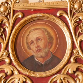 Zdjęcie nr 1: Przedstawienie stanowi jedynie portret świętego, który ma głowę przechyloną na prawo i wzrok skierowany do góry. Bobola ma prostokątną twarz, uniesione brwi, wąski nos i ledwie zaznaczone, zamknięte usta; twarz okala siwa broda, krótkie włosy są zaczesane na boki i do tyłu. Pod szyją widać kawałek czarnej, rozciętej sutanny nałożonej na białą koszulę. Tło jest jednolite, brązowe, jaśniejące wokół głowy świętego otoczonej nimbem. Okrągły obraz ujęto ramką utworzoną z liści laurowych umieszczoną w rozbudowanym obramowaniu w kształcie zbliżonym do stojącego prostokąta o zaoblonych dołem krawędziach. Wypełniają je wychodzące od centralnie umieszczonej palmety sploty płaskorzeźbionej, złotej wici roślinnej z rozwiniętymi kwiatami umieszczone na bordowym tle; górna krawędź dekorowana koronką. 
