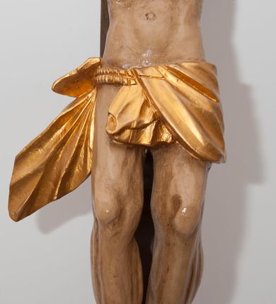 Zdjęcie nr 3: Wizerunek Chrystusa przybitego trzema gwoździami do krzyża.  Ciało wyprostowane, o wyraźnie zaznaczonej linii żeber, długie ręce rozciągnięte powyżej głowy, nogi delikatnie ugięte w kolanach, prawe kolano powyżej lewego. Głowa opada na prawy bark. Jezus ma wielokątną twarz, oczy zamknięte, usta rozchylone, nos prosty; okala ją broda o zaznaczonych pasmach oraz zwijające się w fale włosy opadające na plecy i prawy bark. Na głowie gruba, ciemnozielona korona cierniowa. Biodra otacza złote perizonium ułożone w sztywne, równoległe fałdy i przytrzymane sznurem związanym na prawym boku. W miejscach przebić gwoździami oraz w  ranie w boku ślady krwi. Krzyż gładki, ciemnobrązowy, na górnej belce titulus w formie równoległobocznej tabliczki z literami „INRI” (łac. Iesus Nazarenus Rex Iudaeorum). Polichromia w partiach ciała naturalistyczna. 