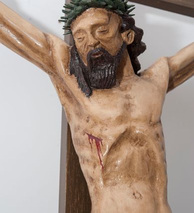 Zdjęcie nr 2: Wizerunek Chrystusa przybitego trzema gwoździami do krzyża.  Ciało wyprostowane, o wyraźnie zaznaczonej linii żeber, długie ręce rozciągnięte powyżej głowy, nogi delikatnie ugięte w kolanach, prawe kolano powyżej lewego. Głowa opada na prawy bark. Jezus ma wielokątną twarz, oczy zamknięte, usta rozchylone, nos prosty; okala ją broda o zaznaczonych pasmach oraz zwijające się w fale włosy opadające na plecy i prawy bark. Na głowie gruba, ciemnozielona korona cierniowa. Biodra otacza złote perizonium ułożone w sztywne, równoległe fałdy i przytrzymane sznurem związanym na prawym boku. W miejscach przebić gwoździami oraz w  ranie w boku ślady krwi. Krzyż gładki, ciemnobrązowy, na górnej belce titulus w formie równoległobocznej tabliczki z literami „INRI” (łac. Iesus Nazarenus Rex Iudaeorum). Polichromia w partiach ciała naturalistyczna. 