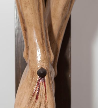 Zdjęcie nr 4: Wizerunek Chrystusa przybitego trzema gwoździami do krzyża.  Ciało wyprostowane, o wyraźnie zaznaczonej linii żeber, długie ręce rozciągnięte powyżej głowy, nogi delikatnie ugięte w kolanach, prawe kolano powyżej lewego. Głowa opada na prawy bark. Jezus ma wielokątną twarz, oczy zamknięte, usta rozchylone, nos prosty; okala ją broda o zaznaczonych pasmach oraz zwijające się w fale włosy opadające na plecy i prawy bark. Na głowie gruba, ciemnozielona korona cierniowa. Biodra otacza złote perizonium ułożone w sztywne, równoległe fałdy i przytrzymane sznurem związanym na prawym boku. W miejscach przebić gwoździami oraz w  ranie w boku ślady krwi. Krzyż gładki, ciemnobrązowy, na górnej belce titulus w formie równoległobocznej tabliczki z literami „INRI” (łac. Iesus Nazarenus Rex Iudaeorum). Polichromia w partiach ciała naturalistyczna. 