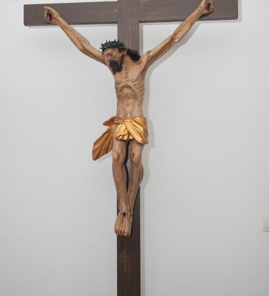 Zdjęcie nr 1: Wizerunek Chrystusa przybitego trzema gwoździami do krzyża.  Ciało wyprostowane, o wyraźnie zaznaczonej linii żeber, długie ręce rozciągnięte powyżej głowy, nogi delikatnie ugięte w kolanach, prawe kolano powyżej lewego. Głowa opada na prawy bark. Jezus ma wielokątną twarz, oczy zamknięte, usta rozchylone, nos prosty; okala ją broda o zaznaczonych pasmach oraz zwijające się w fale włosy opadające na plecy i prawy bark. Na głowie gruba, ciemnozielona korona cierniowa. Biodra otacza złote perizonium ułożone w sztywne, równoległe fałdy i przytrzymane sznurem związanym na prawym boku. W miejscach przebić gwoździami oraz w  ranie w boku ślady krwi. Krzyż gładki, ciemnobrązowy, na górnej belce titulus w formie równoległobocznej tabliczki z literami „INRI” (łac. Iesus Nazarenus Rex Iudaeorum). Polichromia w partiach ciała naturalistyczna. 