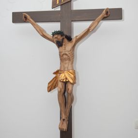 Zdjęcie nr 1: Wizerunek Chrystusa przybitego trzema gwoździami do krzyża.  Ciało wyprostowane, o wyraźnie zaznaczonej linii żeber, długie ręce rozciągnięte powyżej głowy, nogi delikatnie ugięte w kolanach, prawe kolano powyżej lewego. Głowa opada na prawy bark. Jezus ma wielokątną twarz, oczy zamknięte, usta rozchylone, nos prosty; okala ją broda o zaznaczonych pasmach oraz zwijające się w fale włosy opadające na plecy i prawy bark. Na głowie gruba, ciemnozielona korona cierniowa. Biodra otacza złote perizonium ułożone w sztywne, równoległe fałdy i przytrzymane sznurem związanym na prawym boku. W miejscach przebić gwoździami oraz w  ranie w boku ślady krwi. Krzyż gładki, ciemnobrązowy, na górnej belce titulus w formie równoległobocznej tabliczki z literami „INRI” (łac. Iesus Nazarenus Rex Iudaeorum). Polichromia w partiach ciała naturalistyczna. 