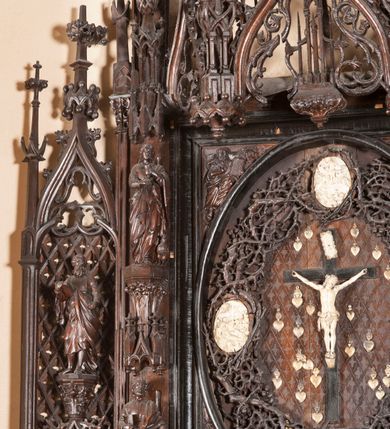 Zdjęcie nr 8: Ołtarz architektoniczny, dwukondygnacyjny ze zwieńczeniem, trójosiowy. Neogotycki na trapezowym postumencie. Mensa wsparta na dwóch  kolumnach o schodkowych, bazach w formie ośmioramiennych gwiazd na siedmiobokach z wklęsłymi ramionami. Z każdego ramienia gwiazd strzeliście unosiła się ku kapitelowi wzdłuż trzonu służka, tworząc u dołu romboidalną, wklęsłą siatkę. Struktura ta zachowała się mniej niż  w połowie na lewej kolumnie. Kapitel lewy ornamentalnie pokryty regularną siatką ze stylizowanych, suchych gałęzi, które tworzą trzy strefy pól ornamentalnych. Dolne przypominają ostre łuki, krzyżują się w nich gałęzie. Środkowe, romboidalne są puste a górne wypełniają sploty suchego akantu. Prawy kapitel posiada podobne podziały pól, różni się wypełnieniem górnej ze stref, gdzie przestrzeń całkowicie zajmują na przemian bujne winne grona oraz pochylające się kłosy zbóż. Zaplecek pod mensą, od frontu podzielono na sześć stref. Na dwóch zewnętrznych i dwóch środkowych znajdują się przedstawienia płaskorzeźbionych łuków okiennych z maswerkami. Druga płaszczyzna od lewej i prawej ozdobiona jest płaskorzeźbą roślinną. Ryzalitowana w części środkowej kondygnacja pierwsza stanowi tabernakulum na cokole. Zadaszenie spadziste pokryte różnorodnym zdobieniem, flankowane czworokątnymi filarami, na których kapitelach wspierają się ramiona ostrych łuków z wimpergami. Powyżej kapitele filarów stanowią blanki z których wyrastają ażurowe formy zbudowane z kilku esownic stylizowane na oset, zakończone profitkami. Widać wnętrze tabernakulum przez ażurowe, dwuskrzydłowe drzwiczki. Na lewych jest przestrzenna rzeźba Orła w koronie osadzona w nieznacznie uszkodzonej oprawie ze splotów gałęzi. Z prawej podobnie wykonane przedstawienie Pogoni Litewskiej. Konny rycerz ma złamany miecz. W centrum ołtarza w prostokątnej ramie znajduje się owalne pole wewnątrz otoczone ciasnym splotem guzowatych gałęzi. W środkowych punktach owalu z gałęzi wstawiono owalne  płaskorzeźby z kości słoniowej ze scenami z życia Chrystusa. W samym środku niewielka rzeźba Jezusa Ukrzyżowanego. Ramę główną flankują postacie Ewangelistów po dwóch z każdej strony, jeden nad drugim, na postumentach i pod gotyckimi baldachimami, najwyższy jest okazalszy. Zwieńczenie ołtarza stanowi wysunięta balustrada zbudowana z ostrołukowych ramion ze sterczynami, centralne ramiona zbiegają się i łączą w sterczynę zakończoną krzyżem. Ołtarz flankowany strzelistymi formami z typowych dla neogotyckiej stylizacji elementami architektonicznymi, w które wkomponowano po jednej postaci świętych z każdej strony.