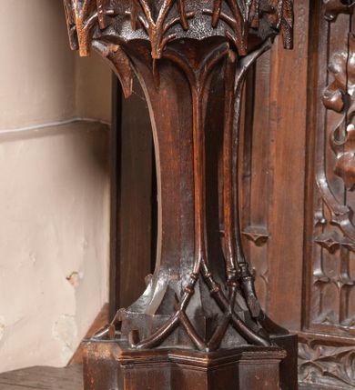 Zdjęcie nr 12: Ołtarz architektoniczny, dwukondygnacyjny ze zwieńczeniem, trójosiowy. Neogotycki na trapezowym postumencie. Mensa wsparta na dwóch  kolumnach o schodkowych, bazach w formie ośmioramiennych gwiazd na siedmiobokach z wklęsłymi ramionami. Z każdego ramienia gwiazd strzeliście unosiła się ku kapitelowi wzdłuż trzonu służka, tworząc u dołu romboidalną, wklęsłą siatkę. Struktura ta zachowała się mniej niż  w połowie na lewej kolumnie. Kapitel lewy ornamentalnie pokryty regularną siatką ze stylizowanych, suchych gałęzi, które tworzą trzy strefy pól ornamentalnych. Dolne przypominają ostre łuki, krzyżują się w nich gałęzie. Środkowe, romboidalne są puste a górne wypełniają sploty suchego akantu. Prawy kapitel posiada podobne podziały pól, różni się wypełnieniem górnej ze stref, gdzie przestrzeń całkowicie zajmują na przemian bujne winne grona oraz pochylające się kłosy zbóż. Zaplecek pod mensą, od frontu podzielono na sześć stref. Na dwóch zewnętrznych i dwóch środkowych znajdują się przedstawienia płaskorzeźbionych łuków okiennych z maswerkami. Druga płaszczyzna od lewej i prawej ozdobiona jest płaskorzeźbą roślinną. Ryzalitowana w części środkowej kondygnacja pierwsza stanowi tabernakulum na cokole. Zadaszenie spadziste pokryte różnorodnym zdobieniem, flankowane czworokątnymi filarami, na których kapitelach wspierają się ramiona ostrych łuków z wimpergami. Powyżej kapitele filarów stanowią blanki z których wyrastają ażurowe formy zbudowane z kilku esownic stylizowane na oset, zakończone profitkami. Widać wnętrze tabernakulum przez ażurowe, dwuskrzydłowe drzwiczki. Na lewych jest przestrzenna rzeźba Orła w koronie osadzona w nieznacznie uszkodzonej oprawie ze splotów gałęzi. Z prawej podobnie wykonane przedstawienie Pogoni Litewskiej. Konny rycerz ma złamany miecz. W centrum ołtarza w prostokątnej ramie znajduje się owalne pole wewnątrz otoczone ciasnym splotem guzowatych gałęzi. W środkowych punktach owalu z gałęzi wstawiono owalne  płaskorzeźby z kości słoniowej ze scenami z życia Chrystusa. W samym środku niewielka rzeźba Jezusa Ukrzyżowanego. Ramę główną flankują postacie Ewangelistów po dwóch z każdej strony, jeden nad drugim, na postumentach i pod gotyckimi baldachimami, najwyższy jest okazalszy. Zwieńczenie ołtarza stanowi wysunięta balustrada zbudowana z ostrołukowych ramion ze sterczynami, centralne ramiona zbiegają się i łączą w sterczynę zakończoną krzyżem. Ołtarz flankowany strzelistymi formami z typowych dla neogotyckiej stylizacji elementami architektonicznymi, w które wkomponowano po jednej postaci świętych z każdej strony.