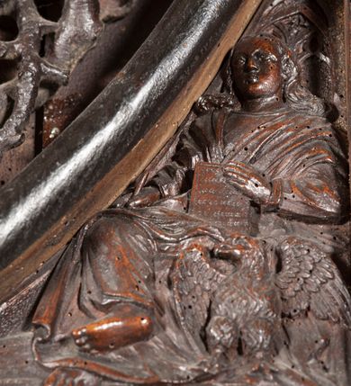 Zdjęcie nr 17: Ołtarz architektoniczny, dwukondygnacyjny ze zwieńczeniem, trójosiowy. Neogotycki na trapezowym postumencie. Mensa wsparta na dwóch  kolumnach o schodkowych, bazach w formie ośmioramiennych gwiazd na siedmiobokach z wklęsłymi ramionami. Z każdego ramienia gwiazd strzeliście unosiła się ku kapitelowi wzdłuż trzonu służka, tworząc u dołu romboidalną, wklęsłą siatkę. Struktura ta zachowała się mniej niż  w połowie na lewej kolumnie. Kapitel lewy ornamentalnie pokryty regularną siatką ze stylizowanych, suchych gałęzi, które tworzą trzy strefy pól ornamentalnych. Dolne przypominają ostre łuki, krzyżują się w nich gałęzie. Środkowe, romboidalne są puste a górne wypełniają sploty suchego akantu. Prawy kapitel posiada podobne podziały pól, różni się wypełnieniem górnej ze stref, gdzie przestrzeń całkowicie zajmują na przemian bujne winne grona oraz pochylające się kłosy zbóż. Zaplecek pod mensą, od frontu podzielono na sześć stref. Na dwóch zewnętrznych i dwóch środkowych znajdują się przedstawienia płaskorzeźbionych łuków okiennych z maswerkami. Druga płaszczyzna od lewej i prawej ozdobiona jest płaskorzeźbą roślinną. Ryzalitowana w części środkowej kondygnacja pierwsza stanowi tabernakulum na cokole. Zadaszenie spadziste pokryte różnorodnym zdobieniem, flankowane czworokątnymi filarami, na których kapitelach wspierają się ramiona ostrych łuków z wimpergami. Powyżej kapitele filarów stanowią blanki z których wyrastają ażurowe formy zbudowane z kilku esownic stylizowane na oset, zakończone profitkami. Widać wnętrze tabernakulum przez ażurowe, dwuskrzydłowe drzwiczki. Na lewych jest przestrzenna rzeźba Orła w koronie osadzona w nieznacznie uszkodzonej oprawie ze splotów gałęzi. Z prawej podobnie wykonane przedstawienie Pogoni Litewskiej. Konny rycerz ma złamany miecz. W centrum ołtarza w prostokątnej ramie znajduje się owalne pole wewnątrz otoczone ciasnym splotem guzowatych gałęzi. W środkowych punktach owalu z gałęzi wstawiono owalne  płaskorzeźby z kości słoniowej ze scenami z życia Chrystusa. W samym środku niewielka rzeźba Jezusa Ukrzyżowanego. Ramę główną flankują postacie Ewangelistów po dwóch z każdej strony, jeden nad drugim, na postumentach i pod gotyckimi baldachimami, najwyższy jest okazalszy. Zwieńczenie ołtarza stanowi wysunięta balustrada zbudowana z ostrołukowych ramion ze sterczynami, centralne ramiona zbiegają się i łączą w sterczynę zakończoną krzyżem. Ołtarz flankowany strzelistymi formami z typowych dla neogotyckiej stylizacji elementami architektonicznymi, w które wkomponowano po jednej postaci świętych z każdej strony.