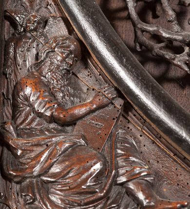 Zdjęcie nr 16: Ołtarz architektoniczny, dwukondygnacyjny ze zwieńczeniem, trójosiowy. Neogotycki na trapezowym postumencie. Mensa wsparta na dwóch  kolumnach o schodkowych, bazach w formie ośmioramiennych gwiazd na siedmiobokach z wklęsłymi ramionami. Z każdego ramienia gwiazd strzeliście unosiła się ku kapitelowi wzdłuż trzonu służka, tworząc u dołu romboidalną, wklęsłą siatkę. Struktura ta zachowała się mniej niż  w połowie na lewej kolumnie. Kapitel lewy ornamentalnie pokryty regularną siatką ze stylizowanych, suchych gałęzi, które tworzą trzy strefy pól ornamentalnych. Dolne przypominają ostre łuki, krzyżują się w nich gałęzie. Środkowe, romboidalne są puste a górne wypełniają sploty suchego akantu. Prawy kapitel posiada podobne podziały pól, różni się wypełnieniem górnej ze stref, gdzie przestrzeń całkowicie zajmują na przemian bujne winne grona oraz pochylające się kłosy zbóż. Zaplecek pod mensą, od frontu podzielono na sześć stref. Na dwóch zewnętrznych i dwóch środkowych znajdują się przedstawienia płaskorzeźbionych łuków okiennych z maswerkami. Druga płaszczyzna od lewej i prawej ozdobiona jest płaskorzeźbą roślinną. Ryzalitowana w części środkowej kondygnacja pierwsza stanowi tabernakulum na cokole. Zadaszenie spadziste pokryte różnorodnym zdobieniem, flankowane czworokątnymi filarami, na których kapitelach wspierają się ramiona ostrych łuków z wimpergami. Powyżej kapitele filarów stanowią blanki z których wyrastają ażurowe formy zbudowane z kilku esownic stylizowane na oset, zakończone profitkami. Widać wnętrze tabernakulum przez ażurowe, dwuskrzydłowe drzwiczki. Na lewych jest przestrzenna rzeźba Orła w koronie osadzona w nieznacznie uszkodzonej oprawie ze splotów gałęzi. Z prawej podobnie wykonane przedstawienie Pogoni Litewskiej. Konny rycerz ma złamany miecz. W centrum ołtarza w prostokątnej ramie znajduje się owalne pole wewnątrz otoczone ciasnym splotem guzowatych gałęzi. W środkowych punktach owalu z gałęzi wstawiono owalne  płaskorzeźby z kości słoniowej ze scenami z życia Chrystusa. W samym środku niewielka rzeźba Jezusa Ukrzyżowanego. Ramę główną flankują postacie Ewangelistów po dwóch z każdej strony, jeden nad drugim, na postumentach i pod gotyckimi baldachimami, najwyższy jest okazalszy. Zwieńczenie ołtarza stanowi wysunięta balustrada zbudowana z ostrołukowych ramion ze sterczynami, centralne ramiona zbiegają się i łączą w sterczynę zakończoną krzyżem. Ołtarz flankowany strzelistymi formami z typowych dla neogotyckiej stylizacji elementami architektonicznymi, w które wkomponowano po jednej postaci świętych z każdej strony.