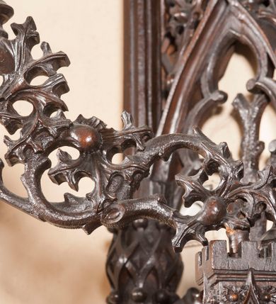 Zdjęcie nr 18: Ołtarz architektoniczny, dwukondygnacyjny ze zwieńczeniem, trójosiowy. Neogotycki na trapezowym postumencie. Mensa wsparta na dwóch  kolumnach o schodkowych, bazach w formie ośmioramiennych gwiazd na siedmiobokach z wklęsłymi ramionami. Z każdego ramienia gwiazd strzeliście unosiła się ku kapitelowi wzdłuż trzonu służka, tworząc u dołu romboidalną, wklęsłą siatkę. Struktura ta zachowała się mniej niż  w połowie na lewej kolumnie. Kapitel lewy ornamentalnie pokryty regularną siatką ze stylizowanych, suchych gałęzi, które tworzą trzy strefy pól ornamentalnych. Dolne przypominają ostre łuki, krzyżują się w nich gałęzie. Środkowe, romboidalne są puste a górne wypełniają sploty suchego akantu. Prawy kapitel posiada podobne podziały pól, różni się wypełnieniem górnej ze stref, gdzie przestrzeń całkowicie zajmują na przemian bujne winne grona oraz pochylające się kłosy zbóż. Zaplecek pod mensą, od frontu podzielono na sześć stref. Na dwóch zewnętrznych i dwóch środkowych znajdują się przedstawienia płaskorzeźbionych łuków okiennych z maswerkami. Druga płaszczyzna od lewej i prawej ozdobiona jest płaskorzeźbą roślinną. Ryzalitowana w części środkowej kondygnacja pierwsza stanowi tabernakulum na cokole. Zadaszenie spadziste pokryte różnorodnym zdobieniem, flankowane czworokątnymi filarami, na których kapitelach wspierają się ramiona ostrych łuków z wimpergami. Powyżej kapitele filarów stanowią blanki z których wyrastają ażurowe formy zbudowane z kilku esownic stylizowane na oset, zakończone profitkami. Widać wnętrze tabernakulum przez ażurowe, dwuskrzydłowe drzwiczki. Na lewych jest przestrzenna rzeźba Orła w koronie osadzona w nieznacznie uszkodzonej oprawie ze splotów gałęzi. Z prawej podobnie wykonane przedstawienie Pogoni Litewskiej. Konny rycerz ma złamany miecz. W centrum ołtarza w prostokątnej ramie znajduje się owalne pole wewnątrz otoczone ciasnym splotem guzowatych gałęzi. W środkowych punktach owalu z gałęzi wstawiono owalne  płaskorzeźby z kości słoniowej ze scenami z życia Chrystusa. W samym środku niewielka rzeźba Jezusa Ukrzyżowanego. Ramę główną flankują postacie Ewangelistów po dwóch z każdej strony, jeden nad drugim, na postumentach i pod gotyckimi baldachimami, najwyższy jest okazalszy. Zwieńczenie ołtarza stanowi wysunięta balustrada zbudowana z ostrołukowych ramion ze sterczynami, centralne ramiona zbiegają się i łączą w sterczynę zakończoną krzyżem. Ołtarz flankowany strzelistymi formami z typowych dla neogotyckiej stylizacji elementami architektonicznymi, w które wkomponowano po jednej postaci świętych z każdej strony.