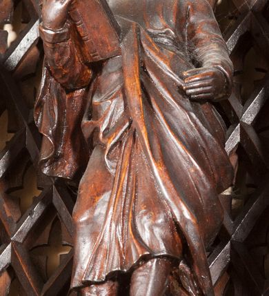 Zdjęcie nr 19: Ołtarz architektoniczny, dwukondygnacyjny ze zwieńczeniem, trójosiowy. Neogotycki na trapezowym postumencie. Mensa wsparta na dwóch  kolumnach o schodkowych, bazach w formie ośmioramiennych gwiazd na siedmiobokach z wklęsłymi ramionami. Z każdego ramienia gwiazd strzeliście unosiła się ku kapitelowi wzdłuż trzonu służka, tworząc u dołu romboidalną, wklęsłą siatkę. Struktura ta zachowała się mniej niż  w połowie na lewej kolumnie. Kapitel lewy ornamentalnie pokryty regularną siatką ze stylizowanych, suchych gałęzi, które tworzą trzy strefy pól ornamentalnych. Dolne przypominają ostre łuki, krzyżują się w nich gałęzie. Środkowe, romboidalne są puste a górne wypełniają sploty suchego akantu. Prawy kapitel posiada podobne podziały pól, różni się wypełnieniem górnej ze stref, gdzie przestrzeń całkowicie zajmują na przemian bujne winne grona oraz pochylające się kłosy zbóż. Zaplecek pod mensą, od frontu podzielono na sześć stref. Na dwóch zewnętrznych i dwóch środkowych znajdują się przedstawienia płaskorzeźbionych łuków okiennych z maswerkami. Druga płaszczyzna od lewej i prawej ozdobiona jest płaskorzeźbą roślinną. Ryzalitowana w części środkowej kondygnacja pierwsza stanowi tabernakulum na cokole. Zadaszenie spadziste pokryte różnorodnym zdobieniem, flankowane czworokątnymi filarami, na których kapitelach wspierają się ramiona ostrych łuków z wimpergami. Powyżej kapitele filarów stanowią blanki z których wyrastają ażurowe formy zbudowane z kilku esownic stylizowane na oset, zakończone profitkami. Widać wnętrze tabernakulum przez ażurowe, dwuskrzydłowe drzwiczki. Na lewych jest przestrzenna rzeźba Orła w koronie osadzona w nieznacznie uszkodzonej oprawie ze splotów gałęzi. Z prawej podobnie wykonane przedstawienie Pogoni Litewskiej. Konny rycerz ma złamany miecz. W centrum ołtarza w prostokątnej ramie znajduje się owalne pole wewnątrz otoczone ciasnym splotem guzowatych gałęzi. W środkowych punktach owalu z gałęzi wstawiono owalne  płaskorzeźby z kości słoniowej ze scenami z życia Chrystusa. W samym środku niewielka rzeźba Jezusa Ukrzyżowanego. Ramę główną flankują postacie Ewangelistów po dwóch z każdej strony, jeden nad drugim, na postumentach i pod gotyckimi baldachimami, najwyższy jest okazalszy. Zwieńczenie ołtarza stanowi wysunięta balustrada zbudowana z ostrołukowych ramion ze sterczynami, centralne ramiona zbiegają się i łączą w sterczynę zakończoną krzyżem. Ołtarz flankowany strzelistymi formami z typowych dla neogotyckiej stylizacji elementami architektonicznymi, w które wkomponowano po jednej postaci świętych z każdej strony.