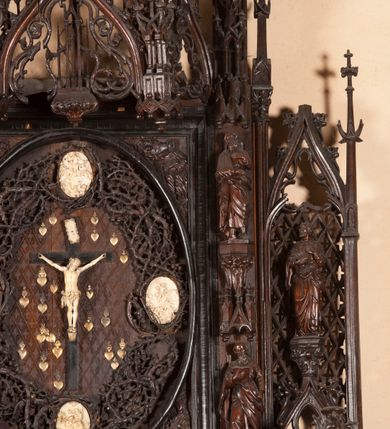 Zdjęcie nr 26: Ołtarz architektoniczny, dwukondygnacyjny ze zwieńczeniem, trójosiowy. Neogotycki na trapezowym postumencie. Mensa wsparta na dwóch  kolumnach o schodkowych, bazach w formie ośmioramiennych gwiazd na siedmiobokach z wklęsłymi ramionami. Z każdego ramienia gwiazd strzeliście unosiła się ku kapitelowi wzdłuż trzonu służka, tworząc u dołu romboidalną, wklęsłą siatkę. Struktura ta zachowała się mniej niż  w połowie na lewej kolumnie. Kapitel lewy ornamentalnie pokryty regularną siatką ze stylizowanych, suchych gałęzi, które tworzą trzy strefy pól ornamentalnych. Dolne przypominają ostre łuki, krzyżują się w nich gałęzie. Środkowe, romboidalne są puste a górne wypełniają sploty suchego akantu. Prawy kapitel posiada podobne podziały pól, różni się wypełnieniem górnej ze stref, gdzie przestrzeń całkowicie zajmują na przemian bujne winne grona oraz pochylające się kłosy zbóż. Zaplecek pod mensą, od frontu podzielono na sześć stref. Na dwóch zewnętrznych i dwóch środkowych znajdują się przedstawienia płaskorzeźbionych łuków okiennych z maswerkami. Druga płaszczyzna od lewej i prawej ozdobiona jest płaskorzeźbą roślinną. Ryzalitowana w części środkowej kondygnacja pierwsza stanowi tabernakulum na cokole. Zadaszenie spadziste pokryte różnorodnym zdobieniem, flankowane czworokątnymi filarami, na których kapitelach wspierają się ramiona ostrych łuków z wimpergami. Powyżej kapitele filarów stanowią blanki z których wyrastają ażurowe formy zbudowane z kilku esownic stylizowane na oset, zakończone profitkami. Widać wnętrze tabernakulum przez ażurowe, dwuskrzydłowe drzwiczki. Na lewych jest przestrzenna rzeźba Orła w koronie osadzona w nieznacznie uszkodzonej oprawie ze splotów gałęzi. Z prawej podobnie wykonane przedstawienie Pogoni Litewskiej. Konny rycerz ma złamany miecz. W centrum ołtarza w prostokątnej ramie znajduje się owalne pole wewnątrz otoczone ciasnym splotem guzowatych gałęzi. W środkowych punktach owalu z gałęzi wstawiono owalne  płaskorzeźby z kości słoniowej ze scenami z życia Chrystusa. W samym środku niewielka rzeźba Jezusa Ukrzyżowanego. Ramę główną flankują postacie Ewangelistów po dwóch z każdej strony, jeden nad drugim, na postumentach i pod gotyckimi baldachimami, najwyższy jest okazalszy. Zwieńczenie ołtarza stanowi wysunięta balustrada zbudowana z ostrołukowych ramion ze sterczynami, centralne ramiona zbiegają się i łączą w sterczynę zakończoną krzyżem. Ołtarz flankowany strzelistymi formami z typowych dla neogotyckiej stylizacji elementami architektonicznymi, w które wkomponowano po jednej postaci świętych z każdej strony.