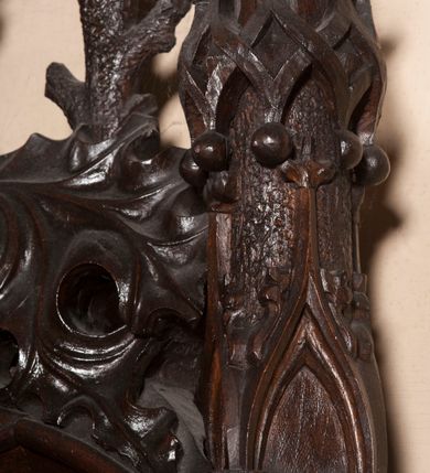 Zdjęcie nr 25: Ołtarz architektoniczny, dwukondygnacyjny ze zwieńczeniem, trójosiowy. Neogotycki na trapezowym postumencie. Mensa wsparta na dwóch  kolumnach o schodkowych, bazach w formie ośmioramiennych gwiazd na siedmiobokach z wklęsłymi ramionami. Z każdego ramienia gwiazd strzeliście unosiła się ku kapitelowi wzdłuż trzonu służka, tworząc u dołu romboidalną, wklęsłą siatkę. Struktura ta zachowała się mniej niż  w połowie na lewej kolumnie. Kapitel lewy ornamentalnie pokryty regularną siatką ze stylizowanych, suchych gałęzi, które tworzą trzy strefy pól ornamentalnych. Dolne przypominają ostre łuki, krzyżują się w nich gałęzie. Środkowe, romboidalne są puste a górne wypełniają sploty suchego akantu. Prawy kapitel posiada podobne podziały pól, różni się wypełnieniem górnej ze stref, gdzie przestrzeń całkowicie zajmują na przemian bujne winne grona oraz pochylające się kłosy zbóż. Zaplecek pod mensą, od frontu podzielono na sześć stref. Na dwóch zewnętrznych i dwóch środkowych znajdują się przedstawienia płaskorzeźbionych łuków okiennych z maswerkami. Druga płaszczyzna od lewej i prawej ozdobiona jest płaskorzeźbą roślinną. Ryzalitowana w części środkowej kondygnacja pierwsza stanowi tabernakulum na cokole. Zadaszenie spadziste pokryte różnorodnym zdobieniem, flankowane czworokątnymi filarami, na których kapitelach wspierają się ramiona ostrych łuków z wimpergami. Powyżej kapitele filarów stanowią blanki z których wyrastają ażurowe formy zbudowane z kilku esownic stylizowane na oset, zakończone profitkami. Widać wnętrze tabernakulum przez ażurowe, dwuskrzydłowe drzwiczki. Na lewych jest przestrzenna rzeźba Orła w koronie osadzona w nieznacznie uszkodzonej oprawie ze splotów gałęzi. Z prawej podobnie wykonane przedstawienie Pogoni Litewskiej. Konny rycerz ma złamany miecz. W centrum ołtarza w prostokątnej ramie znajduje się owalne pole wewnątrz otoczone ciasnym splotem guzowatych gałęzi. W środkowych punktach owalu z gałęzi wstawiono owalne  płaskorzeźby z kości słoniowej ze scenami z życia Chrystusa. W samym środku niewielka rzeźba Jezusa Ukrzyżowanego. Ramę główną flankują postacie Ewangelistów po dwóch z każdej strony, jeden nad drugim, na postumentach i pod gotyckimi baldachimami, najwyższy jest okazalszy. Zwieńczenie ołtarza stanowi wysunięta balustrada zbudowana z ostrołukowych ramion ze sterczynami, centralne ramiona zbiegają się i łączą w sterczynę zakończoną krzyżem. Ołtarz flankowany strzelistymi formami z typowych dla neogotyckiej stylizacji elementami architektonicznymi, w które wkomponowano po jednej postaci świętych z każdej strony.