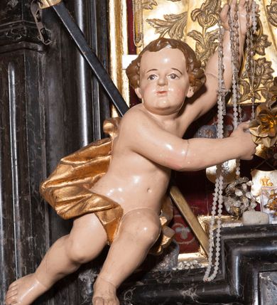 Zdjęcie nr 23: Ołtarz prostopadłościenny, w typie tumbowym, z mensą o brzegu zdobionym rzędem liści akantu naprzemian z łukami kotarowymi zwieńczonymi kulami oraz podwieszonym lambrekinem. Nastawa ołtarzowa jest architektoniczna, jednoosiowa ze zwieńczeniem, ujęta przez kolumny stojące na ukośnie dostawionych cokołach. Kolumny w jednej trzeciej kanelowane w dwóch trzecich skręcone z wplecioną złoconą wicią roślinną, ze złoconym kapitelem podtrzymują przerwany przyczółek ze ślimacznicami, na którym siedzą aniołki. Belkowanie bogato profilowane nad częścią środkową jest wyłamane trzema wklęsłymi łukami. Zwieńczenie jest utworzone z owalnego obrazu z przedstawieniem św. Kingi, w profilowanej ramie ujętej wieńcem z lauru.   

