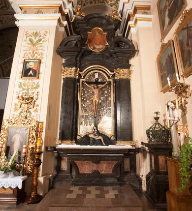 Zdjęcie nr 2: Ołtarz architektoniczny, jednoosiowy, jednokondygnacyjny ze zwieńczeniem. Jego mensa jest w typie tumbowym, antepedium w kształcie płyciny wypełnionej różowym marmurem paczółtowickim, z półkolistymi wcięciami na dłuższych bokach. Nastawa jest ujęta zwielokrotnionymi pilastrami o kompozytowych kapitelach, złoconych, podtrzymujących odcinki belkowania z ćwierćkolistymi naczółkami. Belkowanie połączone w partii architrawu, wygiętego łukowato. Zwieńczenie ujęte spływami wolutowymi, podtrzymującymi gzyms o formie łuku nadwieszonego. W polu środkowym rzeźba Chrystusa na krzyżu, na tle płaskorzeźbionego widoku Jerozolimy, ujętego drewnianą, złoconą ramą w formie stojącego prostokąta, z wyciętą łukowato dolną krawędzią i ściętymi ćwierćkoliście narożami, zwieńczonego podwójnym łukiem półkolistym, nadwieszonym. Na całej powierzchni widoku Jerozolimy ulokowane liczne wota. W zwieńczeniu obraz ze sceną Wskrzeszenia Piotrowina, w fantazyjnie wyciętej ramie o bokach krótszych wybrzuszonych a długich wklęsłych. 

