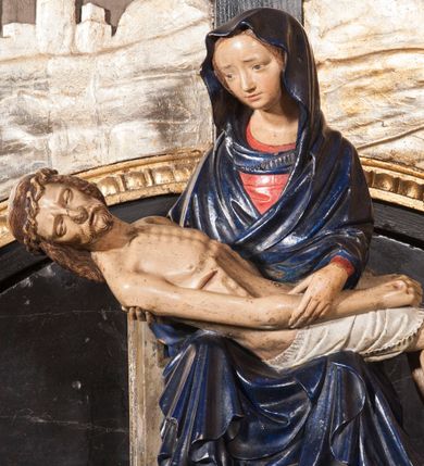 Zdjęcie nr 1: Rzeźba przedstawia siedzącą Marię trzymającą na kolanach ciało swego syna. Maria ustawiona frontalnie, z torsem skręconym lekko w prawo, ubrana w czerwoną suknię i ciemnoniebieski płaszcz z kapturem na głowie. Prawą ręką podtrzymuje syna, a lewą ujmuje go za prawą rękę. Twarz okrągła, pochylona ku Jezusowi, widać na niej boleść; oczy i włosy ciemne, długi nos i zwięzłe usta. Ciało Chrystusa odziane tylko w perizonium spoczywa na kolanach matki, tułów i głowa proste, nogi w kolanach opadają na ziemię, korpus wychudzony tak, że widać żebra i ślady po gwoździach. Głowa w nienaturalnej pozie, prawie w jednej linii z tułowiem, na twarzy widać ból; oczy zamknięte, usta lekko otwarte. Długie do ramion włosy otaczają głowę, lekko zaznaczona broda.