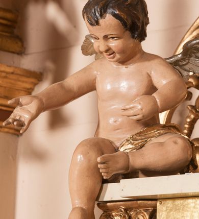 Zdjęcie nr 21: Ołtarz architektoniczny,  przyścienny, trójosiowy, jednokondygnacyjny ze zwieńczeniem. Mensa ołtarzowa kamienna, sarkofagowa, przesłonięta drewnianym antepedium, w centrum którego umieszczono pastorał, krzyż, infułę i księgę w otoczeniu winnej latorośli. Antepedium otoczone ramą ze zdobionymi narożami. Na mensie ustawiono tabernakulum dwukondygnacyjne ze zwieńczeniem, flankowane kolumnami kompozytowymi z pierścieniami w połowie. W dolnej kondygnacji metalowy front z drzwiami o wykroju łuku, zdobionymi splotem kłosów zbóż i kiści winogron. W górnej kondygnacji srebrna płaskorzeźba pelikana karmiącego trzy pisklęta. Po bokach siedzą dwa aniołki. Tabernakulum flankowane stylizowanym przestrzennym ornamentem akantowym. Nastawa posadowiona na wysokim, dekorowanym płycinami, dwudzielnym cokole, którego boczne osie zostały ustawione skośnie w stosunku do głównej. W polu centralnym obraz ze sceną wskrzeszenie Piotrowina przez św. Stanisława w kształcie prostokąta zamkniętego od góry łukiem półkolistym, w złoconej, profilowanej ramie otoczonej srebrnymi orłami oraz stylizowaną wicią roślinną. Powyżej, w zwieńczeniu gloria promienista. W jej centrum Trójca Święta: tronujący wśród obłoków i aniołków Chrystus po lewej stronie i Bóg Ojciec po prawej; powyżej nich unosi się gołębica Ducha Świętego. Otaczająca scenę gloria promienista została skomponowana z wiązek krótszych i dłuższych promieni naprzemiennie srebrnych i złotych, rzadziej rozlokowanych w dolnej części. Boczne osie składają się z ustawionych uskokowo na tle pilastrów par kolumn kompozytowych podtrzymujących rozbudowane, wyłamane na ich osiach belkowanie. Cokoły kolumn są dekorowane płycinami wypełnionymi ornamentem, a między nimi  na konsolach ustawiono figury świętych: Piotra po prawej stronie i Pawła po lewej. Na zewnętrznych częściach belkowania umieszczono woluty, na których posadowiono nagie, przewiązane jedynie złotymi szarfami aniołki wskazujące scenę w glorii. Na wewnętrznych częściach siedzi para większych, ubranych w złoto-czerwone suknie aniołów ukazanych w skręcie, spoglądających we wskazywanym kierunku. 
Ołtarz polichromowany na kolor kremowy, płyciny na ciemnożółty i brązowy, profile również na biało i brązowo; ornamenty, profile, detale oraz kolumny złocone.  
