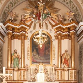 Zdjęcie nr 1: Ołtarz architektoniczny,  przyścienny, trójosiowy, jednokondygnacyjny ze zwieńczeniem. Mensa ołtarzowa kamienna, sarkofagowa, przesłonięta drewnianym antepedium, w centrum którego umieszczono pastorał, krzyż, infułę i księgę w otoczeniu winnej latorośli. Antepedium otoczone ramą ze zdobionymi narożami. Na mensie ustawiono tabernakulum dwukondygnacyjne ze zwieńczeniem, flankowane kolumnami kompozytowymi z pierścieniami w połowie. W dolnej kondygnacji metalowy front z drzwiami o wykroju łuku, zdobionymi splotem kłosów zbóż i kiści winogron. W górnej kondygnacji srebrna płaskorzeźba pelikana karmiącego trzy pisklęta. Po bokach siedzą dwa aniołki. Tabernakulum flankowane stylizowanym przestrzennym ornamentem akantowym. Nastawa posadowiona na wysokim, dekorowanym płycinami, dwudzielnym cokole, którego boczne osie zostały ustawione skośnie w stosunku do głównej. W polu centralnym obraz ze sceną wskrzeszenie Piotrowina przez św. Stanisława w kształcie prostokąta zamkniętego od góry łukiem półkolistym, w złoconej, profilowanej ramie otoczonej srebrnymi orłami oraz stylizowaną wicią roślinną. Powyżej, w zwieńczeniu gloria promienista. W jej centrum Trójca Święta: tronujący wśród obłoków i aniołków Chrystus po lewej stronie i Bóg Ojciec po prawej; powyżej nich unosi się gołębica Ducha Świętego. Otaczająca scenę gloria promienista została skomponowana z wiązek krótszych i dłuższych promieni naprzemiennie srebrnych i złotych, rzadziej rozlokowanych w dolnej części. Boczne osie składają się z ustawionych uskokowo na tle pilastrów par kolumn kompozytowych podtrzymujących rozbudowane, wyłamane na ich osiach belkowanie. Cokoły kolumn są dekorowane płycinami wypełnionymi ornamentem, a między nimi  na konsolach ustawiono figury świętych: Piotra po prawej stronie i Pawła po lewej. Na zewnętrznych częściach belkowania umieszczono woluty, na których posadowiono nagie, przewiązane jedynie złotymi szarfami aniołki wskazujące scenę w glorii. Na wewnętrznych częściach siedzi para większych, ubranych w złoto-czerwone suknie aniołów ukazanych w skręcie, spoglądających we wskazywanym kierunku. 
Ołtarz polichromowany na kolor kremowy, płyciny na ciemnożółty i brązowy, profile również na biało i brązowo; ornamenty, profile, detale oraz kolumny złocone.  
