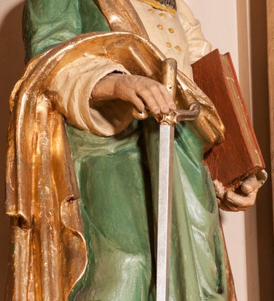 Zdjęcie nr 16: Ołtarz architektoniczny,  przyścienny, trójosiowy, jednokondygnacyjny ze zwieńczeniem. Mensa ołtarzowa kamienna, sarkofagowa, przesłonięta drewnianym antepedium, w centrum którego umieszczono pastorał, krzyż, infułę i księgę w otoczeniu winnej latorośli. Antepedium otoczone ramą ze zdobionymi narożami. Na mensie ustawiono tabernakulum dwukondygnacyjne ze zwieńczeniem, flankowane kolumnami kompozytowymi z pierścieniami w połowie. W dolnej kondygnacji metalowy front z drzwiami o wykroju łuku, zdobionymi splotem kłosów zbóż i kiści winogron. W górnej kondygnacji srebrna płaskorzeźba pelikana karmiącego trzy pisklęta. Po bokach siedzą dwa aniołki. Tabernakulum flankowane stylizowanym przestrzennym ornamentem akantowym. Nastawa posadowiona na wysokim, dekorowanym płycinami, dwudzielnym cokole, którego boczne osie zostały ustawione skośnie w stosunku do głównej. W polu centralnym obraz ze sceną wskrzeszenie Piotrowina przez św. Stanisława w kształcie prostokąta zamkniętego od góry łukiem półkolistym, w złoconej, profilowanej ramie otoczonej srebrnymi orłami oraz stylizowaną wicią roślinną. Powyżej, w zwieńczeniu gloria promienista. W jej centrum Trójca Święta: tronujący wśród obłoków i aniołków Chrystus po lewej stronie i Bóg Ojciec po prawej; powyżej nich unosi się gołębica Ducha Świętego. Otaczająca scenę gloria promienista została skomponowana z wiązek krótszych i dłuższych promieni naprzemiennie srebrnych i złotych, rzadziej rozlokowanych w dolnej części. Boczne osie składają się z ustawionych uskokowo na tle pilastrów par kolumn kompozytowych podtrzymujących rozbudowane, wyłamane na ich osiach belkowanie. Cokoły kolumn są dekorowane płycinami wypełnionymi ornamentem, a między nimi  na konsolach ustawiono figury świętych: Piotra po prawej stronie i Pawła po lewej. Na zewnętrznych częściach belkowania umieszczono woluty, na których posadowiono nagie, przewiązane jedynie złotymi szarfami aniołki wskazujące scenę w glorii. Na wewnętrznych częściach siedzi para większych, ubranych w złoto-czerwone suknie aniołów ukazanych w skręcie, spoglądających we wskazywanym kierunku. 
Ołtarz polichromowany na kolor kremowy, płyciny na ciemnożółty i brązowy, profile również na biało i brązowo; ornamenty, profile, detale oraz kolumny złocone.  
