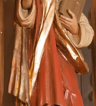 Zdjęcie nr 10: Ołtarz architektoniczny,  przyścienny, trójosiowy, jednokondygnacyjny ze zwieńczeniem. Mensa ołtarzowa kamienna, sarkofagowa, przesłonięta drewnianym antepedium, w centrum którego umieszczono pastorał, krzyż, infułę i księgę w otoczeniu winnej latorośli. Antepedium otoczone ramą ze zdobionymi narożami. Na mensie ustawiono tabernakulum dwukondygnacyjne ze zwieńczeniem, flankowane kolumnami kompozytowymi z pierścieniami w połowie. W dolnej kondygnacji metalowy front z drzwiami o wykroju łuku, zdobionymi splotem kłosów zbóż i kiści winogron. W górnej kondygnacji srebrna płaskorzeźba pelikana karmiącego trzy pisklęta. Po bokach siedzą dwa aniołki. Tabernakulum flankowane stylizowanym przestrzennym ornamentem akantowym. Nastawa posadowiona na wysokim, dekorowanym płycinami, dwudzielnym cokole, którego boczne osie zostały ustawione skośnie w stosunku do głównej. W polu centralnym obraz ze sceną wskrzeszenie Piotrowina przez św. Stanisława w kształcie prostokąta zamkniętego od góry łukiem półkolistym, w złoconej, profilowanej ramie otoczonej srebrnymi orłami oraz stylizowaną wicią roślinną. Powyżej, w zwieńczeniu gloria promienista. W jej centrum Trójca Święta: tronujący wśród obłoków i aniołków Chrystus po lewej stronie i Bóg Ojciec po prawej; powyżej nich unosi się gołębica Ducha Świętego. Otaczająca scenę gloria promienista została skomponowana z wiązek krótszych i dłuższych promieni naprzemiennie srebrnych i złotych, rzadziej rozlokowanych w dolnej części. Boczne osie składają się z ustawionych uskokowo na tle pilastrów par kolumn kompozytowych podtrzymujących rozbudowane, wyłamane na ich osiach belkowanie. Cokoły kolumn są dekorowane płycinami wypełnionymi ornamentem, a między nimi  na konsolach ustawiono figury świętych: Piotra po prawej stronie i Pawła po lewej. Na zewnętrznych częściach belkowania umieszczono woluty, na których posadowiono nagie, przewiązane jedynie złotymi szarfami aniołki wskazujące scenę w glorii. Na wewnętrznych częściach siedzi para większych, ubranych w złoto-czerwone suknie aniołów ukazanych w skręcie, spoglądających we wskazywanym kierunku. 
Ołtarz polichromowany na kolor kremowy, płyciny na ciemnożółty i brązowy, profile również na biało i brązowo; ornamenty, profile, detale oraz kolumny złocone.  
