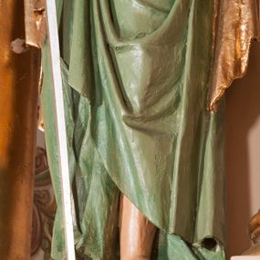 Zdjęcie nr 1: Rzeźba drążona na cokole przedstawiająca św. Pawła ukazanego w całej postaci, zwróconego nieznacznie w lewo. Święty prawą, zgiętą w łokciu ręką trzyma rękojeść opartego o ziemię miecza, lewą podtrzymuje zamkniętą księgę. Ma owalną twarz z dużymi, szeroko otwartymi oczami, prostym nosem oraz wydatnymi ustami; okalają ją ciemnobrązowe, zaczesane do tyłu włosy. Święty ma brodę sięgającą piersi oraz wąsy. Jest ubrany w kremową tunikę z długimi rękawami, zapinaną na guziki i przepasaną w talii oraz zielony płaszcz ze złotym podbiciem przerzucony przez prawe ramię, owijający się wokół bioder i przełożony przez prawą rękę. Tkanina płaszcza spływa do ziemi kaskadowymi fałdami. 
W partiach ciała polichromia naturalistyczna, płaszcz i atrybuty złocone i srebrzone.
