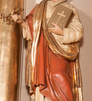Zdjęcie nr 4: Rzeźba drążona na cokole przedstawiająca św. Piotra ukazanego w całej postaci, zwróconego nieznacznie w lewo. Święty prawą, zgiętą w łokciu ręką trzyma dwa złożone razem klucze, lewą podtrzymuje zamkniętą księgę z krzyżem na okładce. Ma owalną, szczupłą twarz z dużymi, szeroko otwartymi oczami, prostym nosem oraz wydatnymi  zakolami; okalają ją ciemnobrązowe, krótkie, zaczesane do tyłu włosy. Święty ma krótką brodę oraz wąsy. Jest ubrany w kremową suknię z kołnierzykiem i długimi rękawami oraz czerwony płaszcz ze złotym podbiciem przerzucony przez prawe ramię, owijający się wokół lewego biodra. Tkanina płaszcza spływa do ziemi podłużnymi, równoległymi fałdami. 
W partiach ciała polichromia naturalistyczna, płaszcz i atrybuty złocone. 
