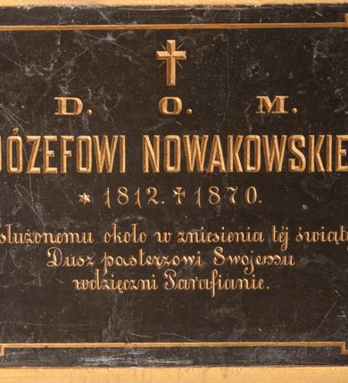 Zdjęcie nr 1: Tablica epitafijna w formie leżącego prostokąta wmurowana w ścianę kościoła. Na środku umieszczono złoconą inskrypcję „D(EO) O(PTIMO) M(AXIMO) / X(KSIĘDZU) JÓZEFOWI NOWAKOWSKIEMU / *1812. +1870. / Zasłużonemu około w zniesienia tej świątyni / Dusz pasterzowi Swojemu / wdzięczni Parafianie”, którą ujęto linią z uszakami w narożach.  