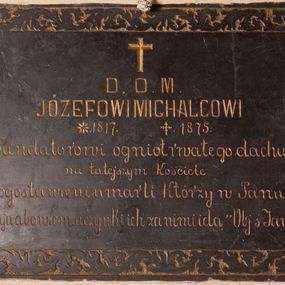 Zdjęcie nr 1: Tablica epitafijna w formie leżącego prostokąta wmurowana w ścianę kościoła. Na środku umieszczono złoconą inskrypcję „D(EO) O(PTIMO) M(AXIMO) / JÓZEFOWI MICHALCOWI / *1817 +1875 / Fundatorowi ogniotrwałego dachu / na tutejszym kościele / Błogosławieni umarli Którzy w Panu / umierają abowiem uczynki ich za nimi idą „Obj(awienie) ś[więtego] Jana XIV 13”. Treść ujęto bordiurą z faliście wijącej się wici roślinnej.   