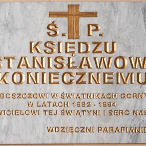 Zdjęcie nr 1: Tablica epitafijna w formie leżącego prostokąta wmurowana w ścianę kościoła. W narożnikach widoczne śruby mocujące, na środku umieszczono złoconą inskrypcję „Ś(WIĘTEJ) P(AMIĘCI) / KSIĘDZU / STANISŁAWOWI / KONIECZNEMU / PROBOSZCZOWI W ŚWIĄTNIKACH GÓRNYCH / W LATACH 1982-1994 / ODNOWICIELOWI TEJ ŚWIĄTYNI I SERC NASZYCH / WDZIĘCZNI PARAFIANIE”. 