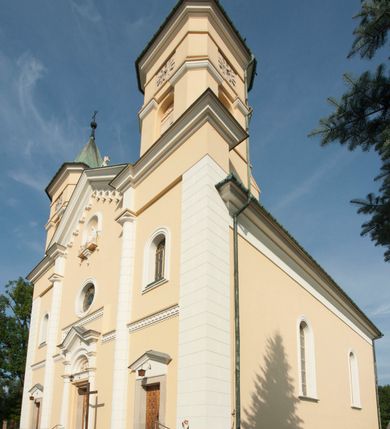Zdjęcie nr 3: Kościół murowany, trójnawowy, halowy, na rzucie prostokąta z wydłużonym, skierowanym na północ prezbiterium z dobudowaną po zachodniej stronie zakrystią. Prezbiterium jednoprzęsłowe, węższe od korpusu, zamknięte prosto. Nawa główna oraz boczne dwuprzęsłowe, rozdzielone masywnymi opilastrowanymi filarami; artykulacja ścian przy pomocy filarów. Sklepienie prezbiterium kolebkowe, naw żagielkowe, przedzielone gurtami. Od południa chór muzyczny mieszczący się między pierwszymi filarami i powyżej kruchty wejściowej. W prezbiterium jedno okno od wschodu, drugie w zakrystii, w nawach bocznych po dwa. Główne wejście od południa flankowane przez dwa boczne, kolejne do zakrystii i między zakrystią i prezbiterium. Niektóre okna wypełnione gomułkami, ściany i sklepienia kościoła pokrywa polichromia utworzona z dekoracji floralnych i umieszczonych w jej obrębie symboli ewangelistów, herbów i putt wykonujących prace kojarzące się z regionem (bartnicze, ślusarskie, kowalskie itd.). Fasada dwuwieżowa, trójosiowa, dwuprzęsłowa, z portalem na każdej osi. Podziały pionowe przeprowadzono za pomocą półkolumienek i lizen, poziome w formie fryzu kostkowego wyniesionego nad środkowym portalem. Drzwi osi głównej w kształcie stojącego prostokąta ujętego półkolumnami dźwigającymi archiwoltę utworzoną z trzech łuków i trójkątny przyczółek. Drzwi osi bocznych zwieńczone przyczółkami. W drugiej kondygnacji na osi okulus i półokrągła konchowa wnęka z figurą Najświętszego Serca Jezusa poniżej trójkątnego szczytu dekorowanego fryzem arkadkowym. W osiach bocznych okna w kształcie stojącego prostokąta zamkniętego półkoliście. Wyżej dwie kondygnacje wież oddzielone gzymsem, w pierwszej  umieszczono okna, w drugiej tarcze zegarów. Elewacje boczne gładkie, przeprute jedynie oknami. Nawy przykrywa dach dwuspadowy, wieże namiotowe z fartuchem zwieńczone krzyżami.