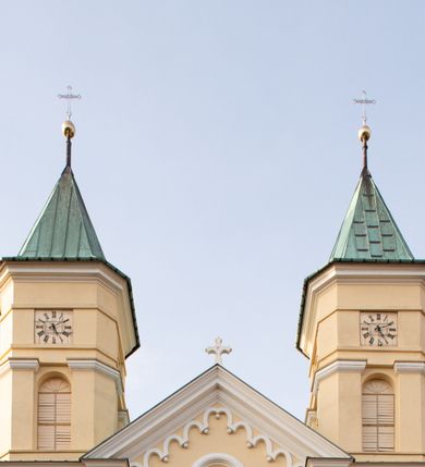 Zdjęcie nr 15: Kościół murowany, trójnawowy, halowy, na rzucie prostokąta z wydłużonym, skierowanym na północ prezbiterium z dobudowaną po zachodniej stronie zakrystią. Prezbiterium jednoprzęsłowe, węższe od korpusu, zamknięte prosto. Nawa główna oraz boczne dwuprzęsłowe, rozdzielone masywnymi opilastrowanymi filarami; artykulacja ścian przy pomocy filarów. Sklepienie prezbiterium kolebkowe, naw żagielkowe, przedzielone gurtami. Od południa chór muzyczny mieszczący się między pierwszymi filarami i powyżej kruchty wejściowej. W prezbiterium jedno okno od wschodu, drugie w zakrystii, w nawach bocznych po dwa. Główne wejście od południa flankowane przez dwa boczne, kolejne do zakrystii i między zakrystią i prezbiterium. Niektóre okna wypełnione gomułkami, ściany i sklepienia kościoła pokrywa polichromia utworzona z dekoracji floralnych i umieszczonych w jej obrębie symboli ewangelistów, herbów i putt wykonujących prace kojarzące się z regionem (bartnicze, ślusarskie, kowalskie itd.). Fasada dwuwieżowa, trójosiowa, dwuprzęsłowa, z portalem na każdej osi. Podziały pionowe przeprowadzono za pomocą półkolumienek i lizen, poziome w formie fryzu kostkowego wyniesionego nad środkowym portalem. Drzwi osi głównej w kształcie stojącego prostokąta ujętego półkolumnami dźwigającymi archiwoltę utworzoną z trzech łuków i trójkątny przyczółek. Drzwi osi bocznych zwieńczone przyczółkami. W drugiej kondygnacji na osi okulus i półokrągła konchowa wnęka z figurą Najświętszego Serca Jezusa poniżej trójkątnego szczytu dekorowanego fryzem arkadkowym. W osiach bocznych okna w kształcie stojącego prostokąta zamkniętego półkoliście. Wyżej dwie kondygnacje wież oddzielone gzymsem, w pierwszej  umieszczono okna, w drugiej tarcze zegarów. Elewacje boczne gładkie, przeprute jedynie oknami. Nawy przykrywa dach dwuspadowy, wieże namiotowe z fartuchem zwieńczone krzyżami.