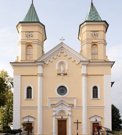 Zdjęcie nr 16: Kościół murowany, trójnawowy, halowy, na rzucie prostokąta z wydłużonym, skierowanym na północ prezbiterium z dobudowaną po zachodniej stronie zakrystią. Prezbiterium jednoprzęsłowe, węższe od korpusu, zamknięte prosto. Nawa główna oraz boczne dwuprzęsłowe, rozdzielone masywnymi opilastrowanymi filarami; artykulacja ścian przy pomocy filarów. Sklepienie prezbiterium kolebkowe, naw żagielkowe, przedzielone gurtami. Od południa chór muzyczny mieszczący się między pierwszymi filarami i powyżej kruchty wejściowej. W prezbiterium jedno okno od wschodu, drugie w zakrystii, w nawach bocznych po dwa. Główne wejście od południa flankowane przez dwa boczne, kolejne do zakrystii i między zakrystią i prezbiterium. Niektóre okna wypełnione gomułkami, ściany i sklepienia kościoła pokrywa polichromia utworzona z dekoracji floralnych i umieszczonych w jej obrębie symboli ewangelistów, herbów i putt wykonujących prace kojarzące się z regionem (bartnicze, ślusarskie, kowalskie itd.). Fasada dwuwieżowa, trójosiowa, dwuprzęsłowa, z portalem na każdej osi. Podziały pionowe przeprowadzono za pomocą półkolumienek i lizen, poziome w formie fryzu kostkowego wyniesionego nad środkowym portalem. Drzwi osi głównej w kształcie stojącego prostokąta ujętego półkolumnami dźwigającymi archiwoltę utworzoną z trzech łuków i trójkątny przyczółek. Drzwi osi bocznych zwieńczone przyczółkami. W drugiej kondygnacji na osi okulus i półokrągła konchowa wnęka z figurą Najświętszego Serca Jezusa poniżej trójkątnego szczytu dekorowanego fryzem arkadkowym. W osiach bocznych okna w kształcie stojącego prostokąta zamkniętego półkoliście. Wyżej dwie kondygnacje wież oddzielone gzymsem, w pierwszej  umieszczono okna, w drugiej tarcze zegarów. Elewacje boczne gładkie, przeprute jedynie oknami. Nawy przykrywa dach dwuspadowy, wieże namiotowe z fartuchem zwieńczone krzyżami.