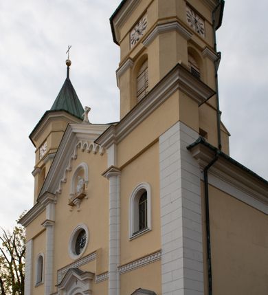 Zdjęcie nr 22: Kościół murowany, trójnawowy, halowy, na rzucie prostokąta z wydłużonym, skierowanym na północ prezbiterium z dobudowaną po zachodniej stronie zakrystią. Prezbiterium jednoprzęsłowe, węższe od korpusu, zamknięte prosto. Nawa główna oraz boczne dwuprzęsłowe, rozdzielone masywnymi opilastrowanymi filarami; artykulacja ścian przy pomocy filarów. Sklepienie prezbiterium kolebkowe, naw żagielkowe, przedzielone gurtami. Od południa chór muzyczny mieszczący się między pierwszymi filarami i powyżej kruchty wejściowej. W prezbiterium jedno okno od wschodu, drugie w zakrystii, w nawach bocznych po dwa. Główne wejście od południa flankowane przez dwa boczne, kolejne do zakrystii i między zakrystią i prezbiterium. Niektóre okna wypełnione gomułkami, ściany i sklepienia kościoła pokrywa polichromia utworzona z dekoracji floralnych i umieszczonych w jej obrębie symboli ewangelistów, herbów i putt wykonujących prace kojarzące się z regionem (bartnicze, ślusarskie, kowalskie itd.). Fasada dwuwieżowa, trójosiowa, dwuprzęsłowa, z portalem na każdej osi. Podziały pionowe przeprowadzono za pomocą półkolumienek i lizen, poziome w formie fryzu kostkowego wyniesionego nad środkowym portalem. Drzwi osi głównej w kształcie stojącego prostokąta ujętego półkolumnami dźwigającymi archiwoltę utworzoną z trzech łuków i trójkątny przyczółek. Drzwi osi bocznych zwieńczone przyczółkami. W drugiej kondygnacji na osi okulus i półokrągła konchowa wnęka z figurą Najświętszego Serca Jezusa poniżej trójkątnego szczytu dekorowanego fryzem arkadkowym. W osiach bocznych okna w kształcie stojącego prostokąta zamkniętego półkoliście. Wyżej dwie kondygnacje wież oddzielone gzymsem, w pierwszej  umieszczono okna, w drugiej tarcze zegarów. Elewacje boczne gładkie, przeprute jedynie oknami. Nawy przykrywa dach dwuspadowy, wieże namiotowe z fartuchem zwieńczone krzyżami.