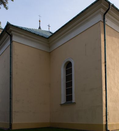 Zdjęcie nr 23: Kościół murowany, trójnawowy, halowy, na rzucie prostokąta z wydłużonym, skierowanym na północ prezbiterium z dobudowaną po zachodniej stronie zakrystią. Prezbiterium jednoprzęsłowe, węższe od korpusu, zamknięte prosto. Nawa główna oraz boczne dwuprzęsłowe, rozdzielone masywnymi opilastrowanymi filarami; artykulacja ścian przy pomocy filarów. Sklepienie prezbiterium kolebkowe, naw żagielkowe, przedzielone gurtami. Od południa chór muzyczny mieszczący się między pierwszymi filarami i powyżej kruchty wejściowej. W prezbiterium jedno okno od wschodu, drugie w zakrystii, w nawach bocznych po dwa. Główne wejście od południa flankowane przez dwa boczne, kolejne do zakrystii i między zakrystią i prezbiterium. Niektóre okna wypełnione gomułkami, ściany i sklepienia kościoła pokrywa polichromia utworzona z dekoracji floralnych i umieszczonych w jej obrębie symboli ewangelistów, herbów i putt wykonujących prace kojarzące się z regionem (bartnicze, ślusarskie, kowalskie itd.). Fasada dwuwieżowa, trójosiowa, dwuprzęsłowa, z portalem na każdej osi. Podziały pionowe przeprowadzono za pomocą półkolumienek i lizen, poziome w formie fryzu kostkowego wyniesionego nad środkowym portalem. Drzwi osi głównej w kształcie stojącego prostokąta ujętego półkolumnami dźwigającymi archiwoltę utworzoną z trzech łuków i trójkątny przyczółek. Drzwi osi bocznych zwieńczone przyczółkami. W drugiej kondygnacji na osi okulus i półokrągła konchowa wnęka z figurą Najświętszego Serca Jezusa poniżej trójkątnego szczytu dekorowanego fryzem arkadkowym. W osiach bocznych okna w kształcie stojącego prostokąta zamkniętego półkoliście. Wyżej dwie kondygnacje wież oddzielone gzymsem, w pierwszej  umieszczono okna, w drugiej tarcze zegarów. Elewacje boczne gładkie, przeprute jedynie oknami. Nawy przykrywa dach dwuspadowy, wieże namiotowe z fartuchem zwieńczone krzyżami.