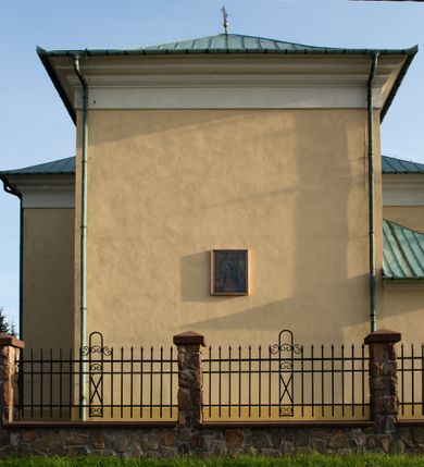 Zdjęcie nr 25: Kościół murowany, trójnawowy, halowy, na rzucie prostokąta z wydłużonym, skierowanym na północ prezbiterium z dobudowaną po zachodniej stronie zakrystią. Prezbiterium jednoprzęsłowe, węższe od korpusu, zamknięte prosto. Nawa główna oraz boczne dwuprzęsłowe, rozdzielone masywnymi opilastrowanymi filarami; artykulacja ścian przy pomocy filarów. Sklepienie prezbiterium kolebkowe, naw żagielkowe, przedzielone gurtami. Od południa chór muzyczny mieszczący się między pierwszymi filarami i powyżej kruchty wejściowej. W prezbiterium jedno okno od wschodu, drugie w zakrystii, w nawach bocznych po dwa. Główne wejście od południa flankowane przez dwa boczne, kolejne do zakrystii i między zakrystią i prezbiterium. Niektóre okna wypełnione gomułkami, ściany i sklepienia kościoła pokrywa polichromia utworzona z dekoracji floralnych i umieszczonych w jej obrębie symboli ewangelistów, herbów i putt wykonujących prace kojarzące się z regionem (bartnicze, ślusarskie, kowalskie itd.). Fasada dwuwieżowa, trójosiowa, dwuprzęsłowa, z portalem na każdej osi. Podziały pionowe przeprowadzono za pomocą półkolumienek i lizen, poziome w formie fryzu kostkowego wyniesionego nad środkowym portalem. Drzwi osi głównej w kształcie stojącego prostokąta ujętego półkolumnami dźwigającymi archiwoltę utworzoną z trzech łuków i trójkątny przyczółek. Drzwi osi bocznych zwieńczone przyczółkami. W drugiej kondygnacji na osi okulus i półokrągła konchowa wnęka z figurą Najświętszego Serca Jezusa poniżej trójkątnego szczytu dekorowanego fryzem arkadkowym. W osiach bocznych okna w kształcie stojącego prostokąta zamkniętego półkoliście. Wyżej dwie kondygnacje wież oddzielone gzymsem, w pierwszej  umieszczono okna, w drugiej tarcze zegarów. Elewacje boczne gładkie, przeprute jedynie oknami. Nawy przykrywa dach dwuspadowy, wieże namiotowe z fartuchem zwieńczone krzyżami.