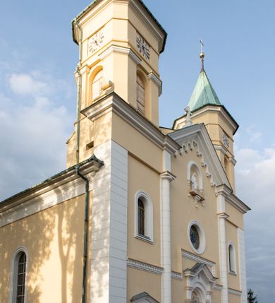 Zdjęcie nr 35: Kościół murowany, trójnawowy, halowy, na rzucie prostokąta z wydłużonym, skierowanym na północ prezbiterium z dobudowaną po zachodniej stronie zakrystią. Prezbiterium jednoprzęsłowe, węższe od korpusu, zamknięte prosto. Nawa główna oraz boczne dwuprzęsłowe, rozdzielone masywnymi opilastrowanymi filarami; artykulacja ścian przy pomocy filarów. Sklepienie prezbiterium kolebkowe, naw żagielkowe, przedzielone gurtami. Od południa chór muzyczny mieszczący się między pierwszymi filarami i powyżej kruchty wejściowej. W prezbiterium jedno okno od wschodu, drugie w zakrystii, w nawach bocznych po dwa. Główne wejście od południa flankowane przez dwa boczne, kolejne do zakrystii i między zakrystią i prezbiterium. Niektóre okna wypełnione gomułkami, ściany i sklepienia kościoła pokrywa polichromia utworzona z dekoracji floralnych i umieszczonych w jej obrębie symboli ewangelistów, herbów i putt wykonujących prace kojarzące się z regionem (bartnicze, ślusarskie, kowalskie itd.). Fasada dwuwieżowa, trójosiowa, dwuprzęsłowa, z portalem na każdej osi. Podziały pionowe przeprowadzono za pomocą półkolumienek i lizen, poziome w formie fryzu kostkowego wyniesionego nad środkowym portalem. Drzwi osi głównej w kształcie stojącego prostokąta ujętego półkolumnami dźwigającymi archiwoltę utworzoną z trzech łuków i trójkątny przyczółek. Drzwi osi bocznych zwieńczone przyczółkami. W drugiej kondygnacji na osi okulus i półokrągła konchowa wnęka z figurą Najświętszego Serca Jezusa poniżej trójkątnego szczytu dekorowanego fryzem arkadkowym. W osiach bocznych okna w kształcie stojącego prostokąta zamkniętego półkoliście. Wyżej dwie kondygnacje wież oddzielone gzymsem, w pierwszej  umieszczono okna, w drugiej tarcze zegarów. Elewacje boczne gładkie, przeprute jedynie oknami. Nawy przykrywa dach dwuspadowy, wieże namiotowe z fartuchem zwieńczone krzyżami.