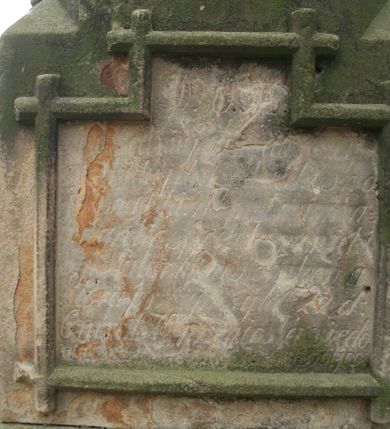 Zdjęcie nr 2: Nagrobek wolnostojący złożony z dwustrefowego cokołu podtrzymującego dwustrefowy korpus zwieńczony krzyżem łacińskim. Cokół jest gładki, dolna część niższa i szersza od górnej. Dolna część korpusu jest prostopadłościenna, na frontowej ścianie, wmurowano w ramę w kształcie leżącego prostokąta z uskokiem marmurową płytę z inskrypcją „D(eo) O(ptimo) M(aximo) / Ś(więtej) P(amięci) / TU SPOCZYWA / Kś. JAK SŁOMKA / PARAFIANIN / ZMARŁ w 36 ROKU ŻYCIA / PO 9 LATACH KAPŁAŃSTWA / w 1874 r(oku) / POKÓJ JEGO DUSZY / ODN(OWILI) PARAFIANIE 1981” poniżej rytego w piaskowcu „D(eo) O(ptimo) M(aximo)”. Na tylnej ścianie, w takiej samej ramie znajduje się nieczytelny napis zaczynający się od „D(eo) O(ptimo) M(aximo)”. Górna część korpusu jest  wieloboczna, smuklejsza i wyższa niż dolna, zakończona gzymsem. Każdą jej ściankę dekoruje ostrołukowa blenda. Całość wieńczy krzyż łaciński o ramionach stylizowanych na utworzone z gałęzi. 

