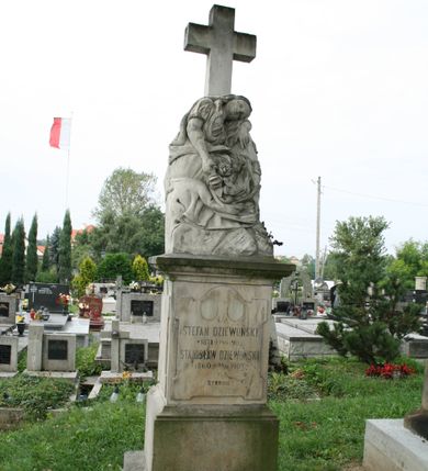 Zdjęcie nr 1: Nagrobek wolnostojący złożony z cokołu na dwustopniowej podstawie, na którym posadowiono rzeźbę zwieńczoną krzyżem. Podstawa gładka, dolna część szersza i niższa niż górna. Cokół zwieńczony wydatnym, profilowanym gzymsem. Na jego frontowej ścianie, na tablicy w kształcie stojącego prostokąta zamkniętego od góry łukiem nadwieszonym, z uszakami w narożach dwa miejsca na medaliony oraz inskrypcja „Ś(WIĘTEJ) P(AMIĘCI) / STEFAN DZIEWOŃSKI / 1871 + 19/9 1903 / STANISŁAW DZIEWOŃSKI / *1860 +22/11 1907 / SYNOWIE”. 
Z tyłu nagrobka „Ś(WIĘTEJ) P(AMIĘCI) / TEKLA DZIEWOŃSKA / PRZEŻYWSZY LAT 76. / +31/7 1907. / SPOKÓJ ICH DUSZOM”. Na cokole ustawiono rzeźbę zrozpaczonej kobiety, która siedzi na skałach, głowę składa na lewej ręce opartej o kamień, w prawej trzyma rozwinięte róże. Spod bogato marszczonej sukni z krótkimi rękawami wystaje goła stopa; na głowie welon opadający na plecy. Z tyłu rzeźba imituje ułożone na sobie kamienie. Kompozycję wieńczy gładki krzyż łaciński. 