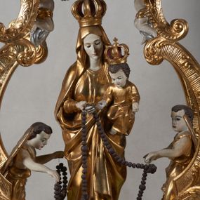 Zdjęcie nr 1: Na profilowanym, prostopadłościennym postumencie ustawiona pełnoplastyczna figura Matki Boskiej z Dzieciątkiem stojącej na niebieskim globie ziemskim, depczącej węża z czerwonym jabłkiem w pysku i podtrzymującej  różaniec. Maria jest ubrana w długie, złocone szaty, na lewym ręku podtrzymuje analogicznie ubrane Dzieciątko. Obie postaci w koronach zamkniętych. Po bokach i na górze pełnoplastyczne wizerunki aniołków siedzących na obłokach i podtrzymujących części różańca oraz różany wieniec nad głową Marii. Całość otoczona ażurową strukturą utworzoną z esowato akantowo-rocaille'owych wygiętych wolut, na których ustawiony jest bogato dekorowany lambrekinem baldachim. W zwieńczeniu gloria promienista z monogramem maryjnym w obłokach. Odsłonięte partie ciała postaci polichromowane naturalistycznie, pozostałe fragmenty srebrzone i złocone; postument w kolorze jasnozielonym ze złoconymi profilami.