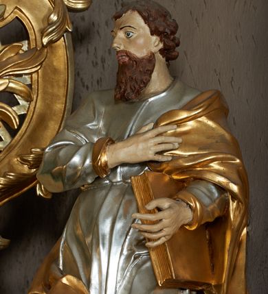 Zdjęcie nr 3: Rzeźba pełna, ustawiona frontalnie, o esowatym układzie ciała. Prawa ręka świętego spoczywa na piersi, przytrzymując płaszcz, lewa ugięta, trzyma księgę na lewym biodrze. Głowę ma zwróconą w trzech czwartych w prawo, twarz podłużną, mały nos, wyraźnie otwarte oczy i delikatnie rozchylone usta; okoloną zarostem w postaci długiej brody spływającej na pierś; włosy krótkie, w formie loków. Święty jest ubrany w obficie marszczoną tunikę, ściśle przylegającą do ciała, która spływa w dół w postaci prostych, głęboko rzeźbionych fałd. Płaszcz zawieszony na lewym ramieniu otacza postać, zawijając się na prawym udzie; tkanina ekspresyjnie poruszona, silnie łamana, drapowana w gęste fałdy. Polichromia naturalistyczna w partiach ciała, tunika srebrzona, płaszcz i księga złocone.