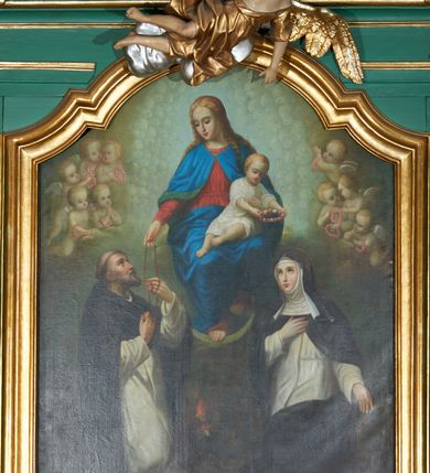 Zdjęcie nr 2: Obraz w formie stojącego prostokąta zamkniętego łukiem nadwieszonym z uskokiem. W centrum tronuje Maria z Dzieciątkiem na kolanach i półksiężycem pod prawą stopą. Postać jest ustawiona frontalnie, delikatnie pochyla głowę w prawo. Prawą ręką wysuniętą w przód podaje różaniec św. Dominikowi, lewą obejmuje Dzieciątko. Maria ma twarz o młodzieńczych, delikatnych rysach, z wyraźnie zarysowanym długim nosem, półprzymkniętymi powiekami. Jasne włosy z przedziałkiem pośrodku, opadają  zwinięte w pukle na ramiona i plecy. Maria jest ubrana w czerwoną tunikę przepasaną w talii oraz niebieski płaszcz spięty na piersi zaponą, przerzucony z przodu przez kolana. Dzieciątko zwrócone w trzech czwartych w prawo, z korpusem skierowanym w lewo; delikatnie pochylone; obiema dłońmi trzyma wieniec z kwiatów nad głową św. Katarzyny. Ma okrągłą twarz o wyraźnych rysach, wysokie czoło, okrągłe oczy, małe usta i nos; włosy krótkie, jasne, układające się w loki. Jest ubrane w białą tunikę w podwiniętymi rękawami. Po lewej stronie, klęcząca postać św. Dominika, ukazanego w całej postaci, z prawego profilu. Święty prawą rękę składa na piersi, lewą odbiera różaniec od Marii. Głowę ma uniesioną lekko ku górze, twarz szczupłą, o ostrym profilu nosa, wzrok kieruje na Marię; włosy krótkie z tonsurą, krótka broda. Święty ubrany jest w habit dominikański. U jego stóp brązowy pies z pochodnią w pysku. Po prawej stronie obrazu postać klęczącej św. Katarzyny Sieneńskiej ukazanej w całej postaci, zwróconej w prawo, z lewą ręką opuszczoną, prawą zaś złożoną na piersi. Twarz świętej jest owalna, o dziewczęcych rysach i jasnej karnacji, wzrok skierowany ku górze w stronę Marii, nos długi o prostym profilu, usta niewielkie. U góry kompozycji, po bokach Marii uskrzydlone, nagie putta trzymające różane wianki. Tło szaro-zielonkawe wypełnione powtarzającym się motywem główek anielskich.